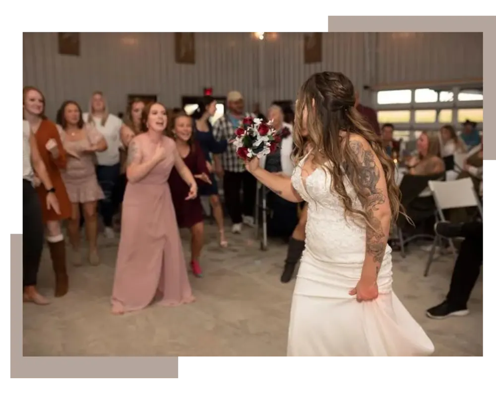 Bride tossing her bouquet to guests during the reception inside the barn